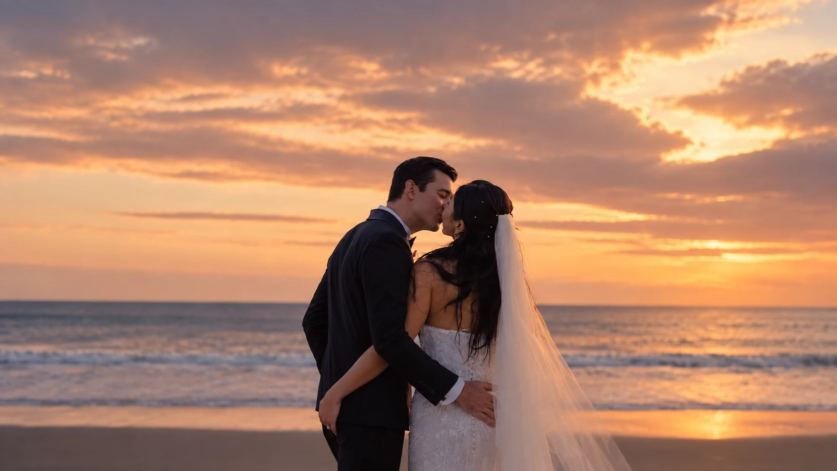 Pasangan pengantin berciuman di pantai saat matahari terbenam